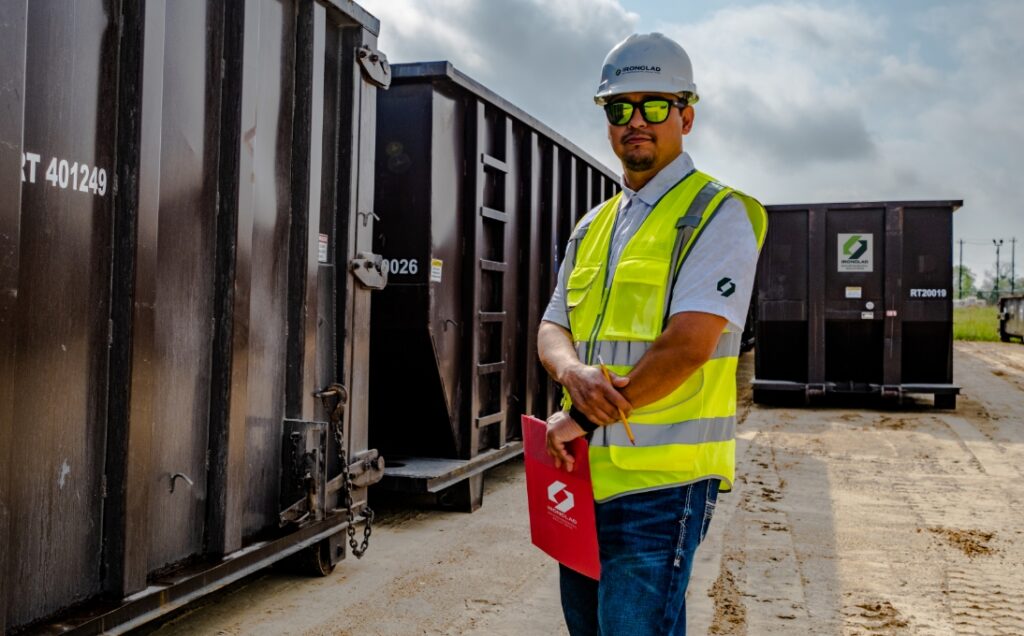 Ironclad employee posing in front of 40yd roll off bins