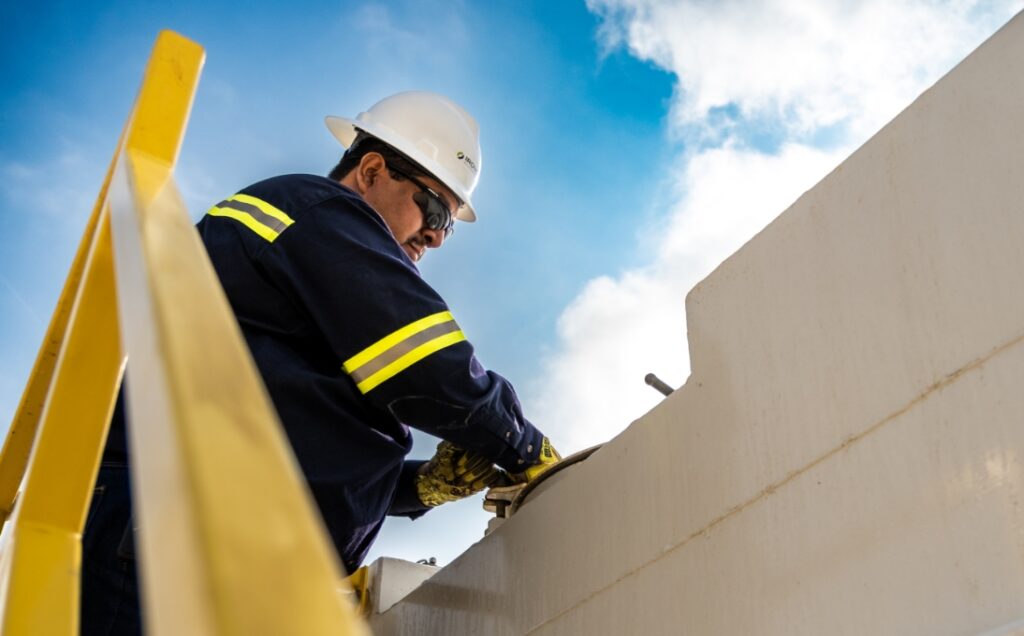 Ironclad employee securing cover on top of closed top steel tank